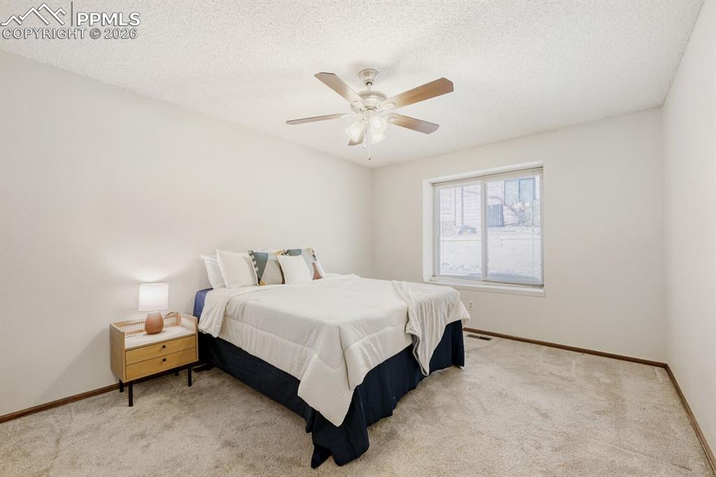 Bedroom with light colored carpet, a ceiling fan, and a textured ceiling