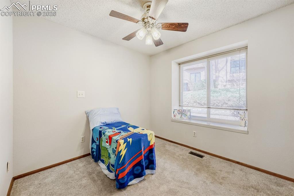 Bedroom with a textured ceiling, ceiling fan, and carpet