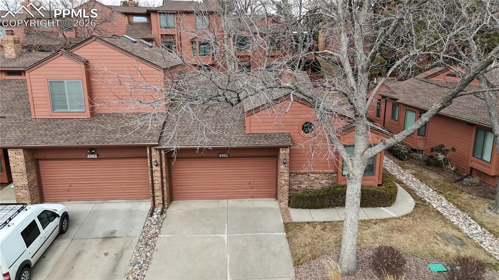 Chalet / cabin featuring brick siding, driveway, roof with shingles, and an attached garage