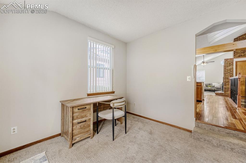 Office featuring light colored carpet, beam ceiling, and a ceiling fan
