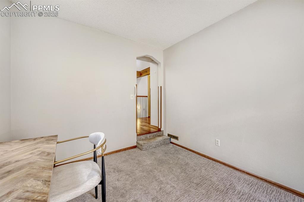 Unfurnished office with arched walkways, carpet floors, and a textured ceiling