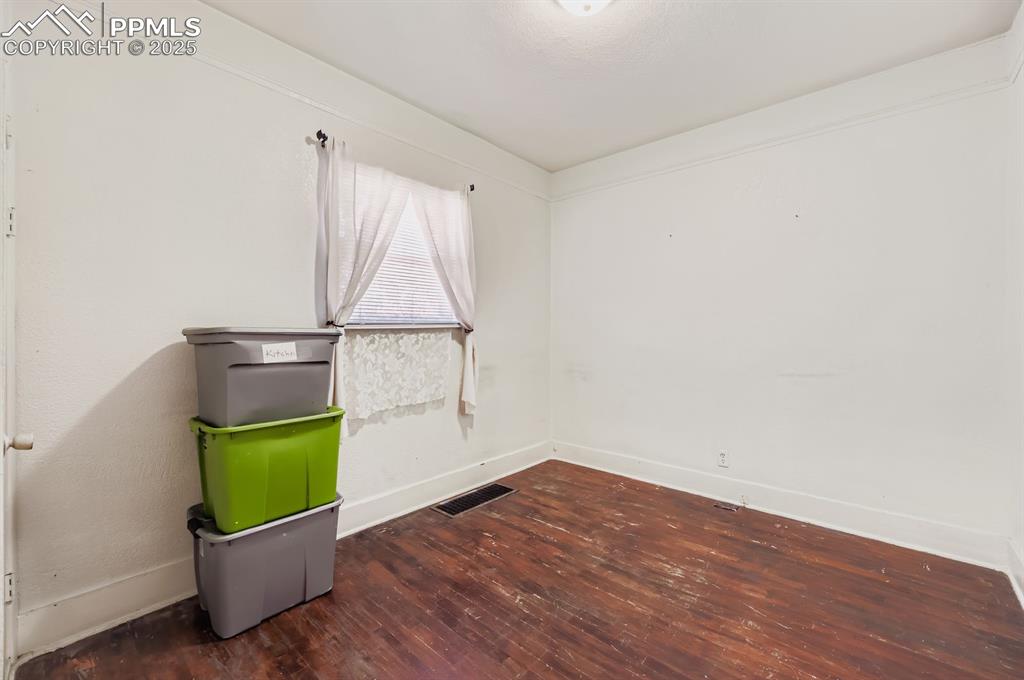 Spare room featuring dark wood-style flooring and baseboards