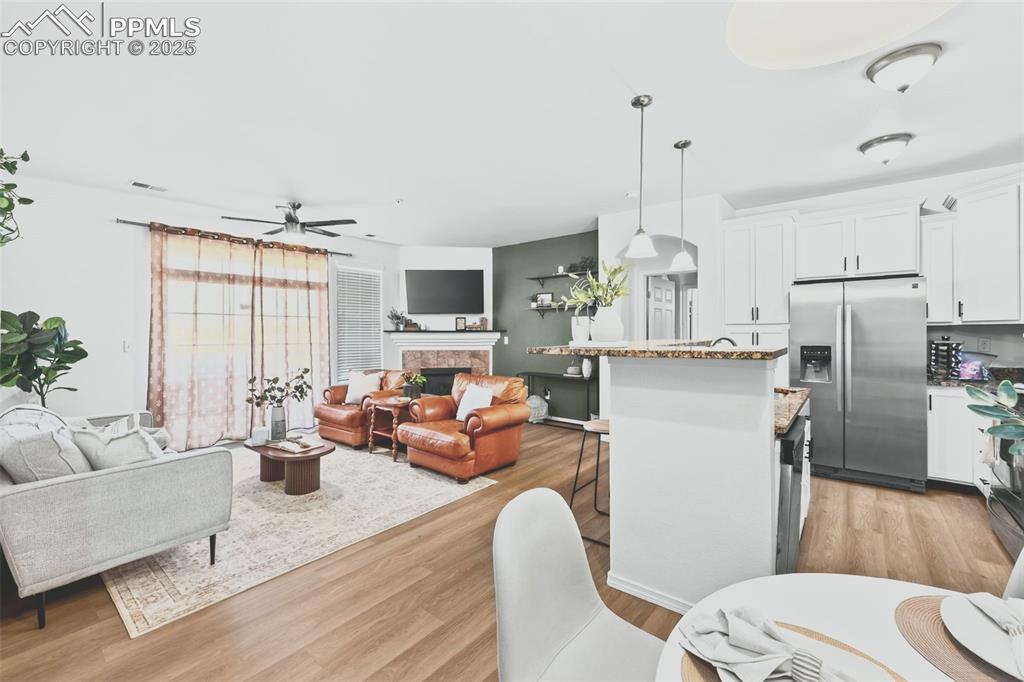 Living room with light wood finished floors, a ceiling fan, and a high end fireplace