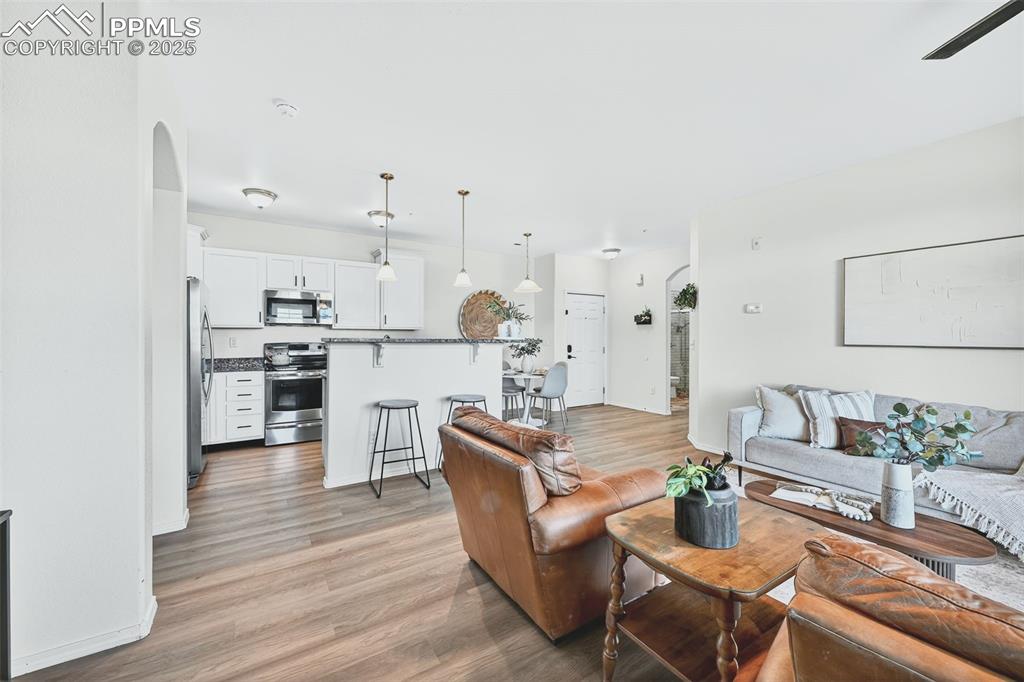 Living room with arched walkways and light wood-style floors