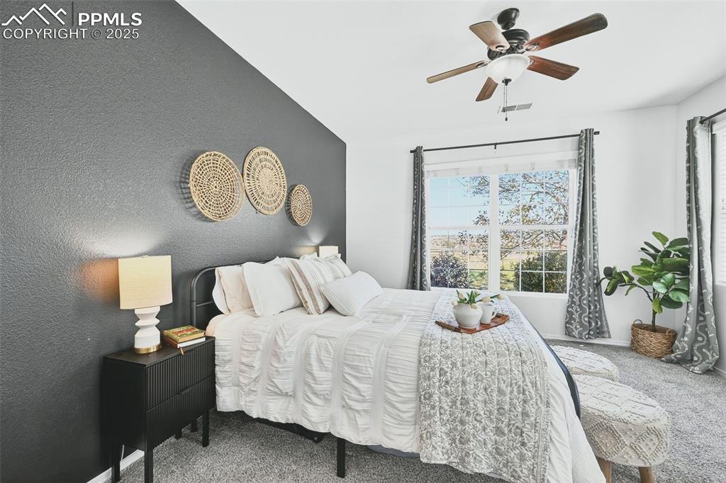 Bedroom with carpet flooring, a textured wall, and ceiling fan