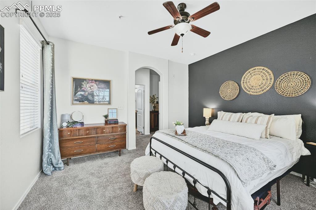 Carpeted bedroom featuring ceiling fan and arched walkways