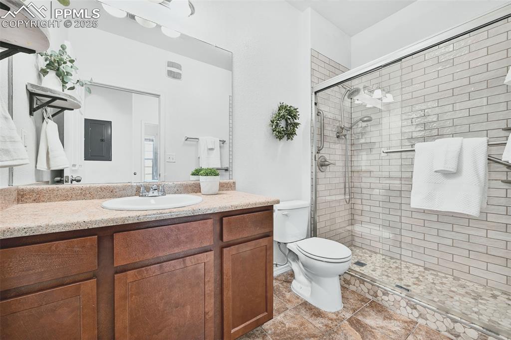 Full bathroom with vanity, a new walk-in stall shower, electric panel, and light tile patterned floors