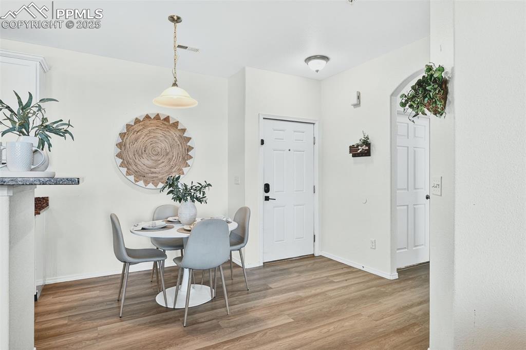 Dining area featuring light wood finished floors and arched walkways