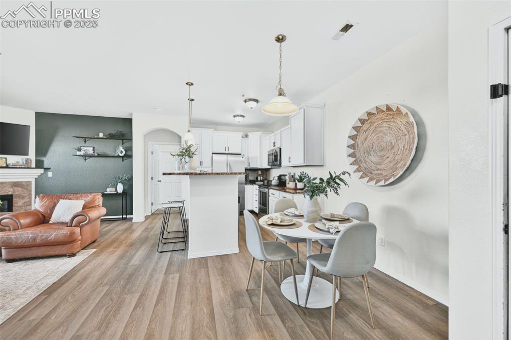 Dining area featuring light wood-type flooring and a fireplace