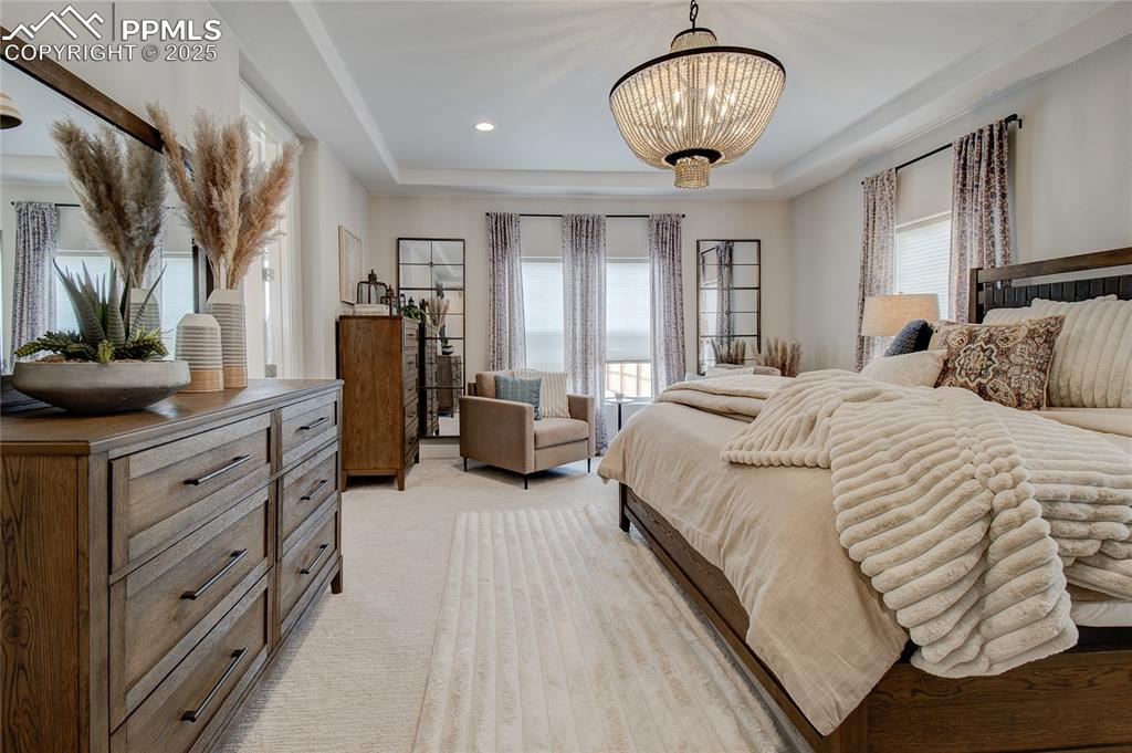 Bedroom featuring a tray ceiling, light carpet, recessed lighting, and a chandelier