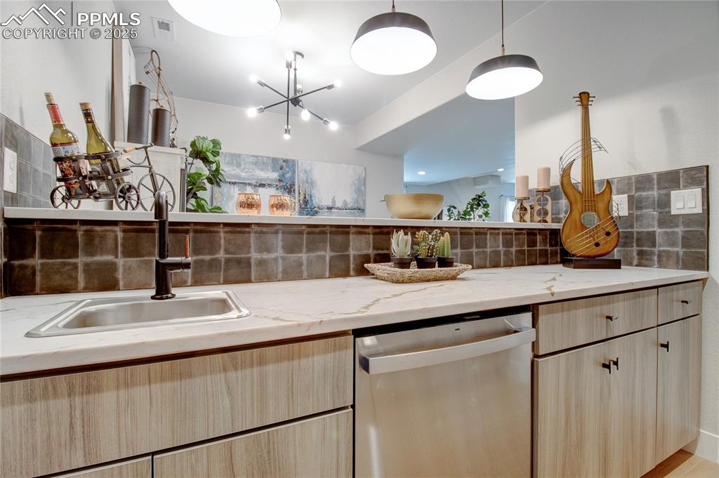 Kitchen with light brown cabinets, stainless steel dishwasher, and tasteful backsplash