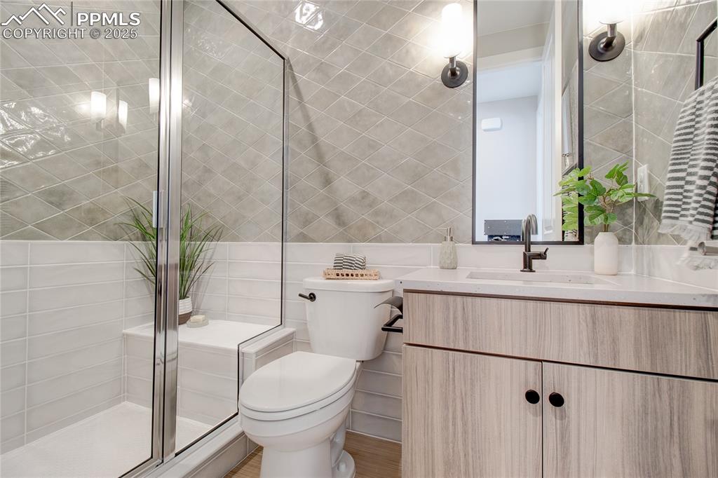 Full bath featuring tile walls, vanity, and a shower stall