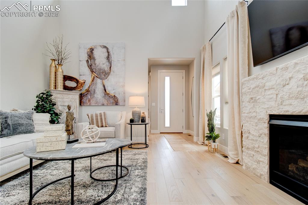 Living room with a fireplace, hardwood / wood-style floors, and a towering ceiling