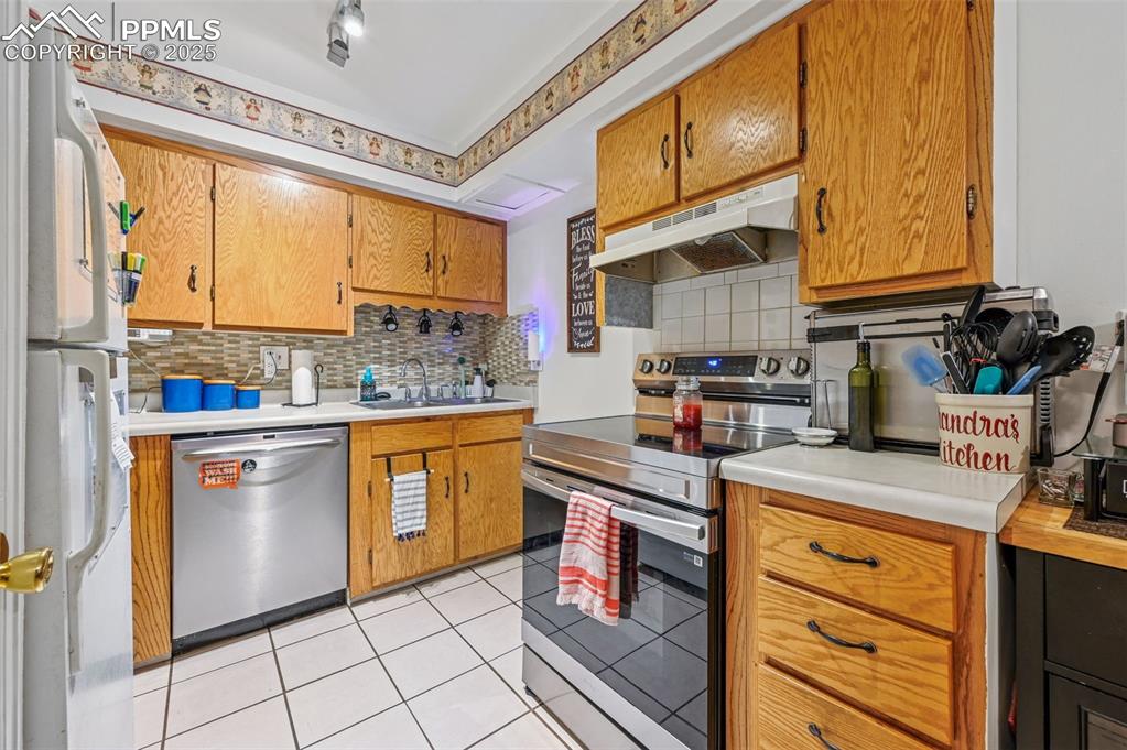 Kitchen featuring stainless steel appliances, light countertops, and decorative backsplash