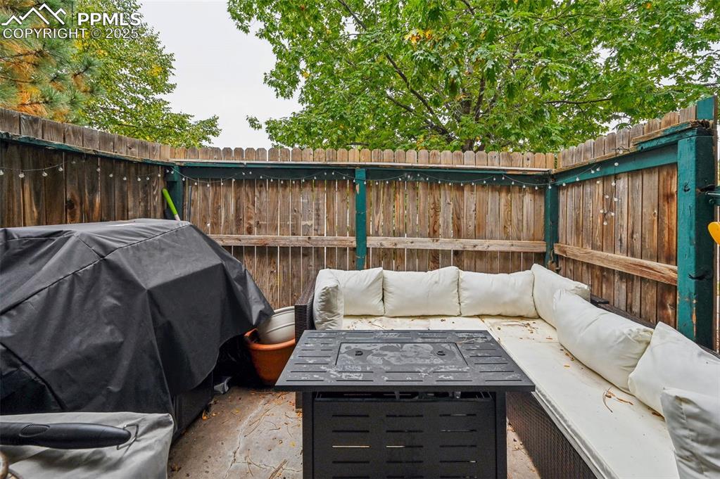 Fenced backyard featuring an outdoor living space with a fire pit and area for grilling