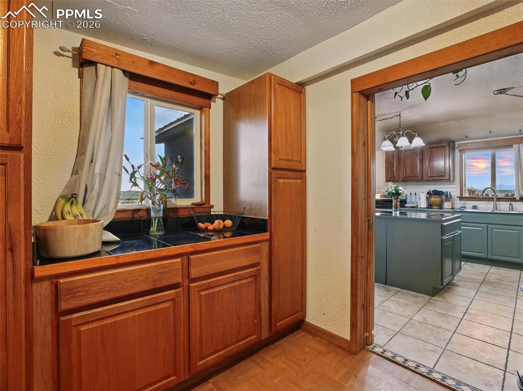 Kitchen featuring a textured wall, dark countertops, a textured ceiling, parquet flooring, and wood finish cabinets