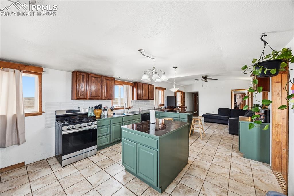 Kitchen featuring a center island, dark countertops, gas stove, a peninsula, and green cabinets
