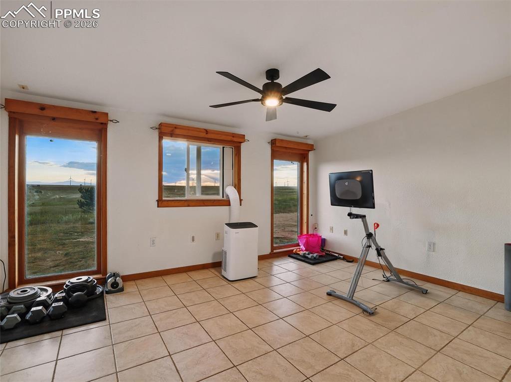 Exercise area with a ceiling fan and light tile patterned flooring