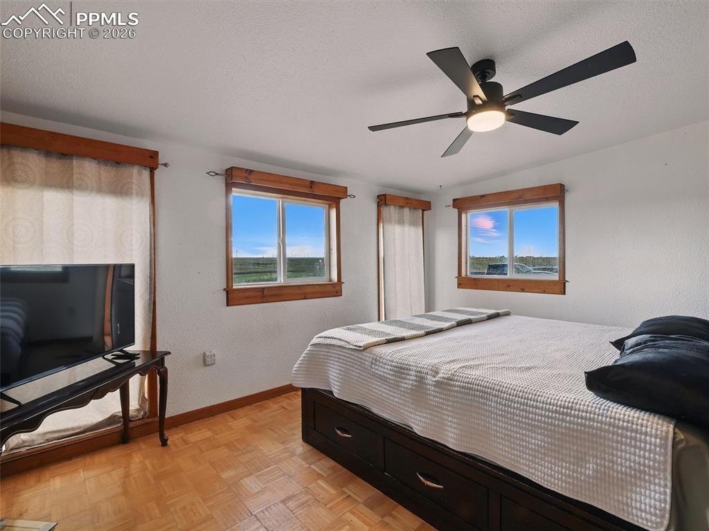 Bedroom with parquet floors, a textured ceiling, a ceiling fan, and a textured wall