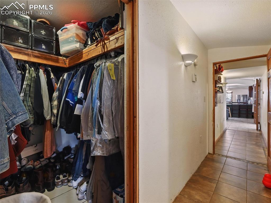 Walk in closet featuring light tile patterned floors and vaulted ceiling