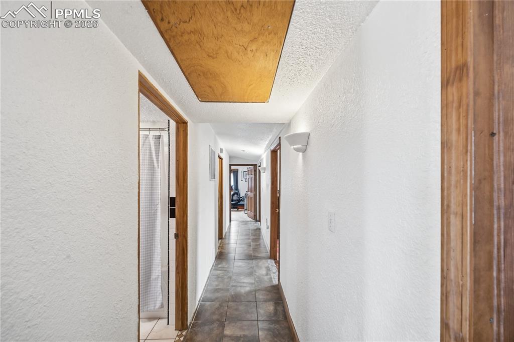 Hall featuring a textured wall and a textured ceiling