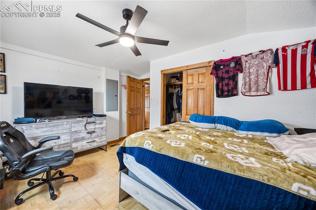 Bedroom featuring a closet, parquet floors, a ceiling fan, and electric panel