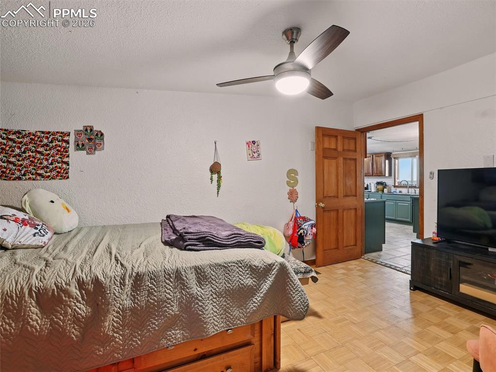 Bedroom featuring parquet floors, a ceiling fan, a textured ceiling, and a textured wall