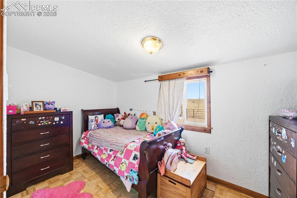 Bedroom featuring parquet flooring, a textured ceiling, and a textured wall