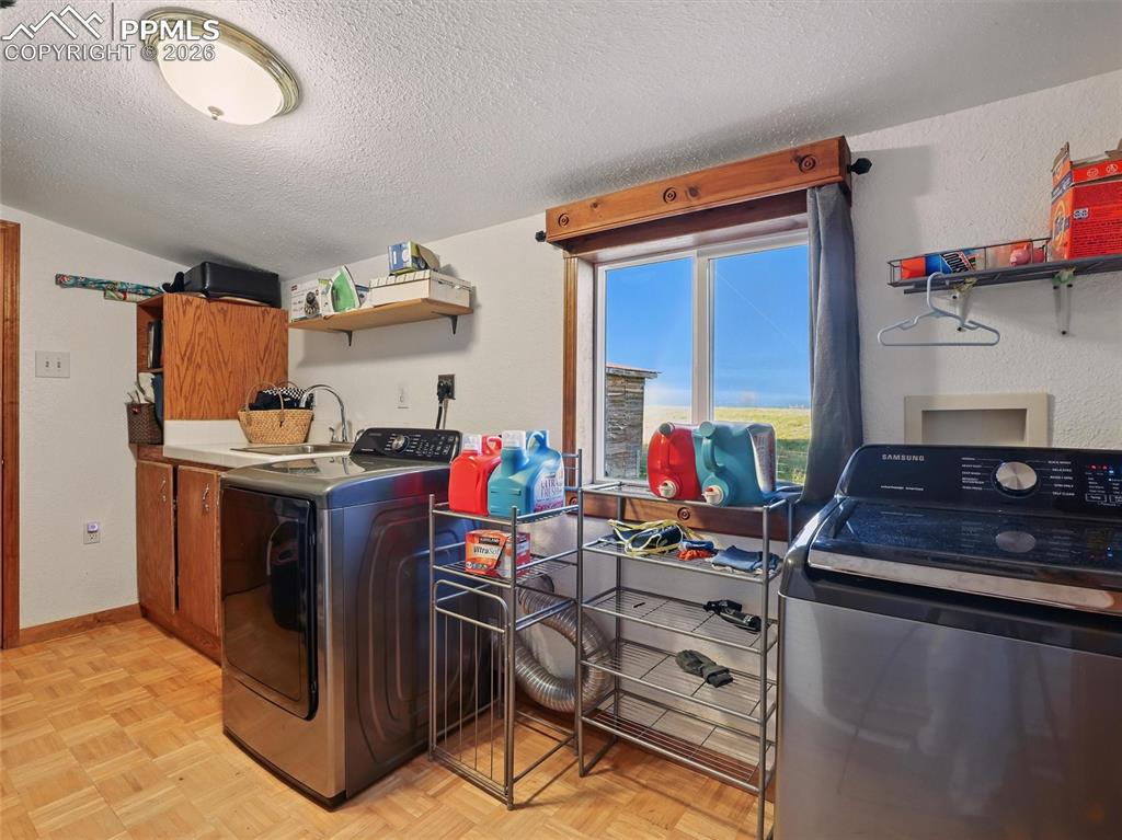 Laundry room with a textured ceiling, separate washer and dryer, and parquet floors