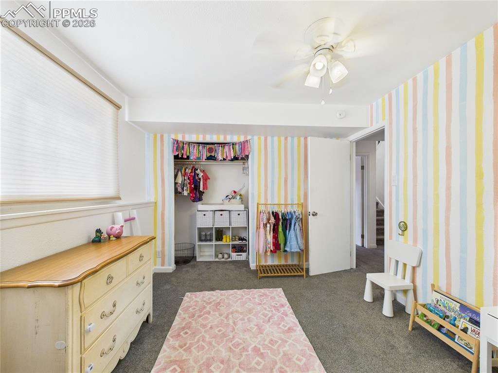 Bedroom with dark carpet, a ceiling fan, and a closet