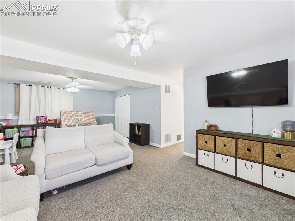 Living area featuring ceiling fan and carpet floors