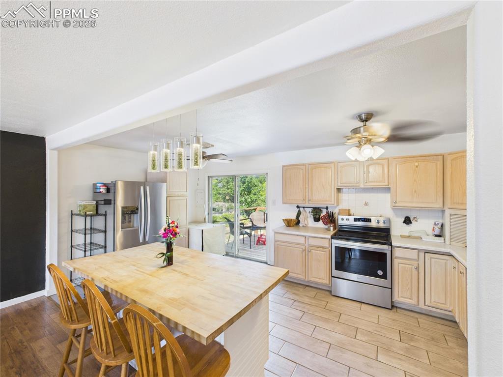 Kitchen featuring light wood finish cabinets, stainless steel appliances, a breakfast bar area, and wood tiled floors