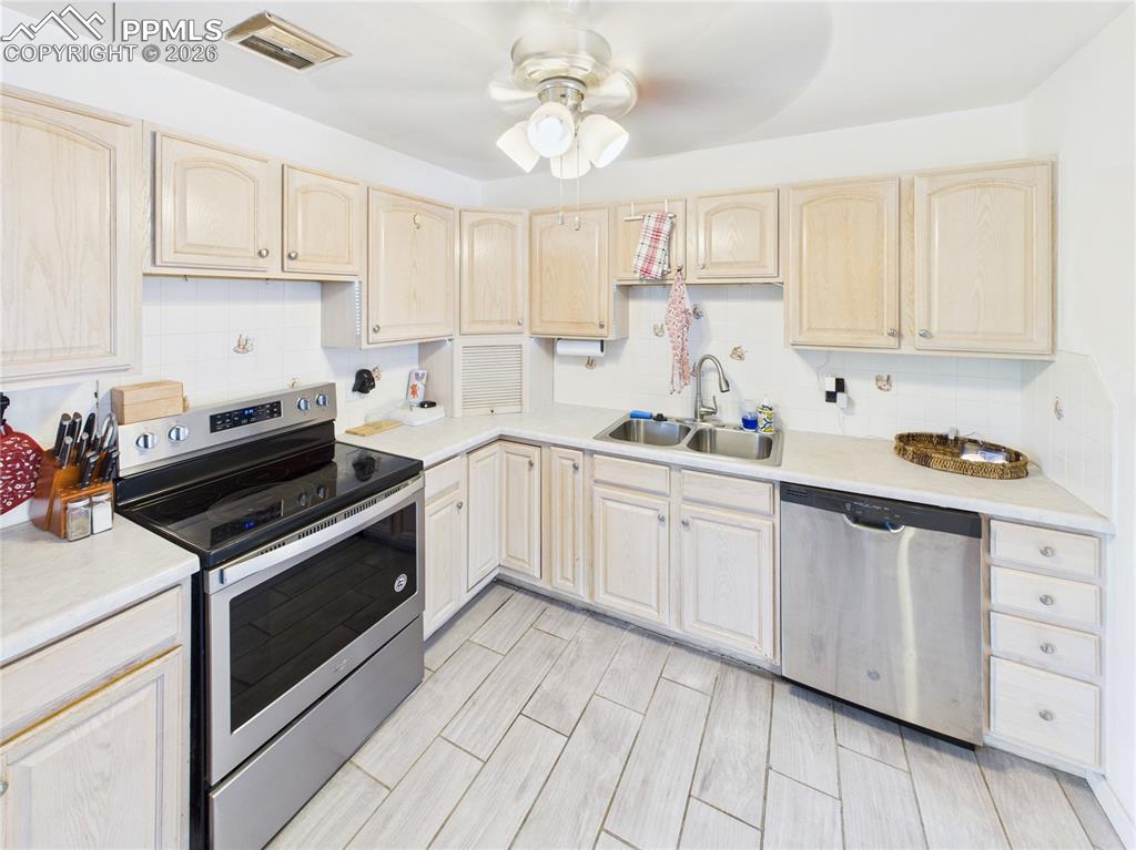 Kitchen featuring stainless steel appliances, light wood finish cabinets, and light countertops