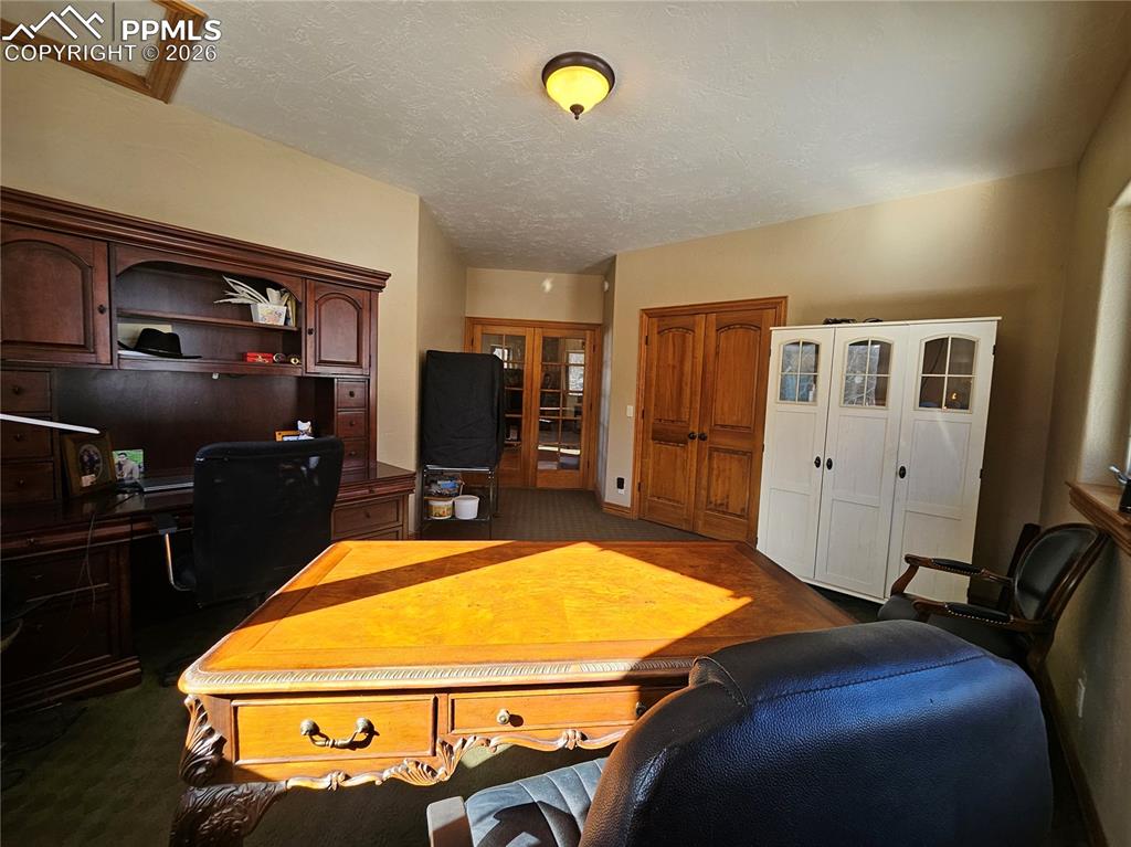 Office featuring dark colored carpet, French doors, with a closet