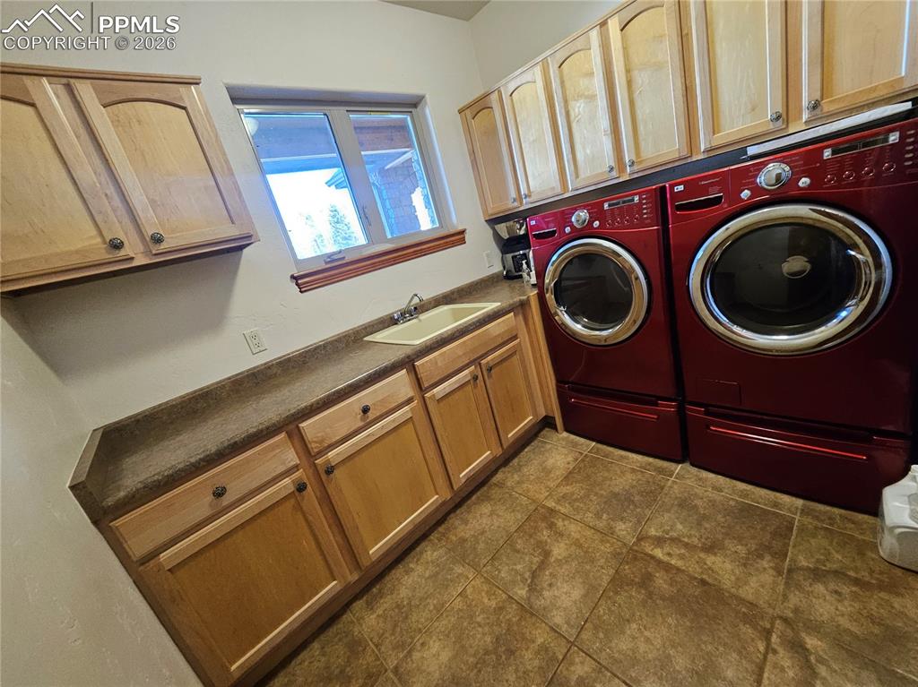 Laundry area featuring separate washer and dryer, cabinet space, and dark tile patterned flooring