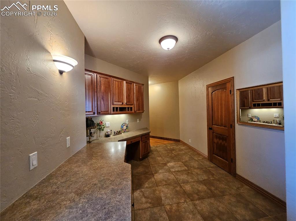 Mud Room off of garage with built in study area, wood finish cabinets, and light countertops