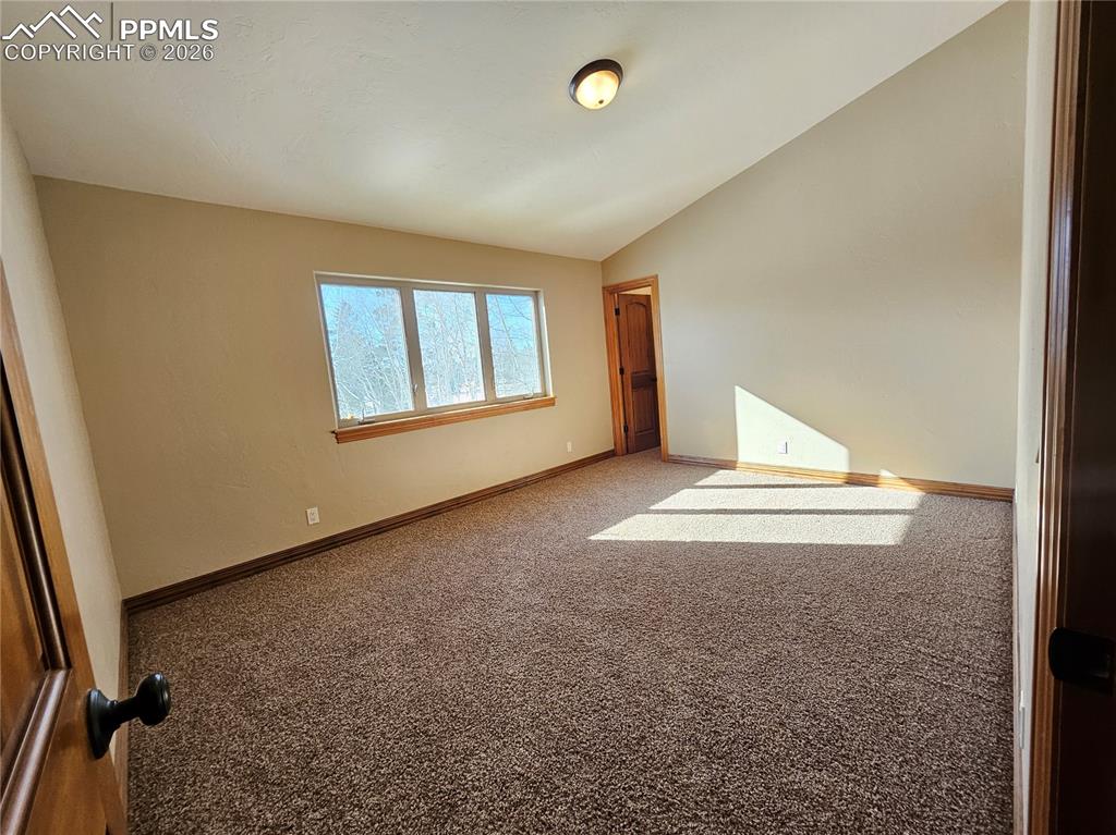 Carpeted bedroom upstairs with vaulted ceiling and walk-in closet