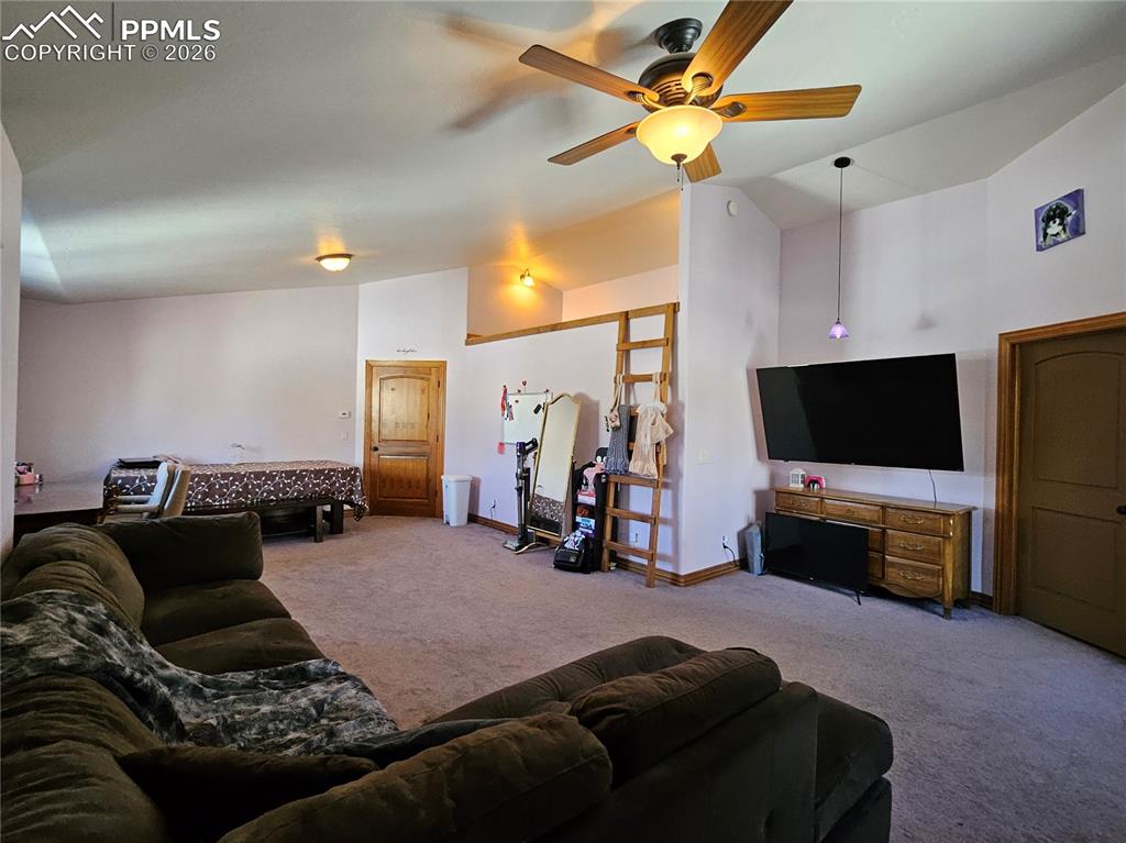 Carpeted bedroom featuring vaulted ceiling and a ceiling fan - being used as a secondary living room