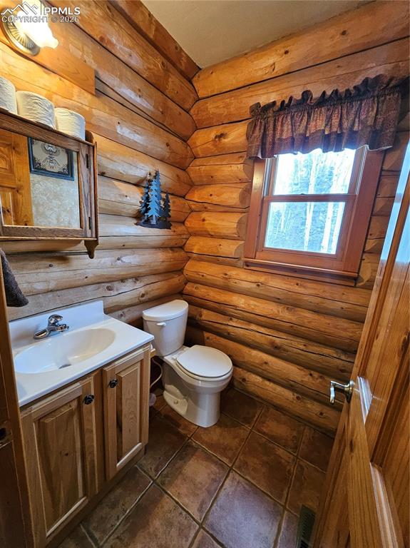 Half bathroom in cabin with vanity and log walls