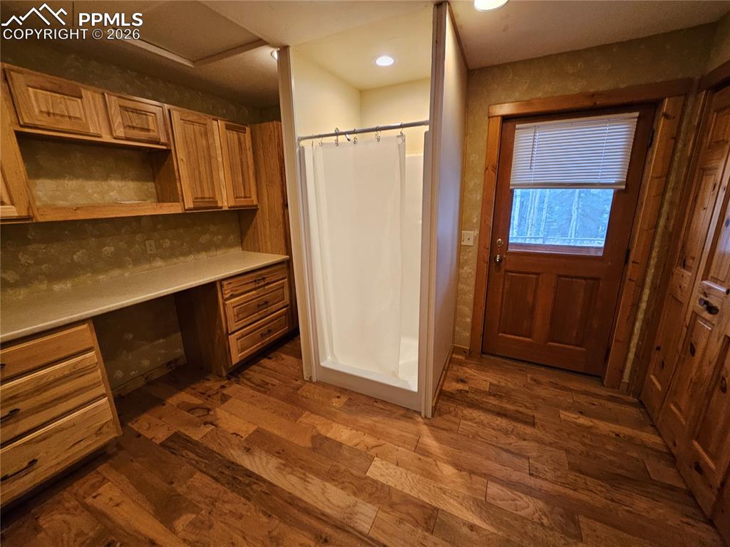 Cabin laundry room featuring a stall shower, dark wood finished floors, closet, and folding vanity