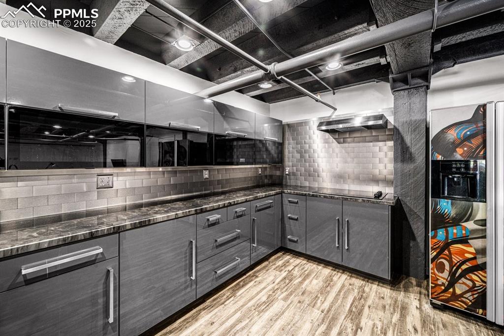 Kitchen featuring gray cabinetry, light wood-style flooring, backsplash, dark stone countertops, and black electric cooktop