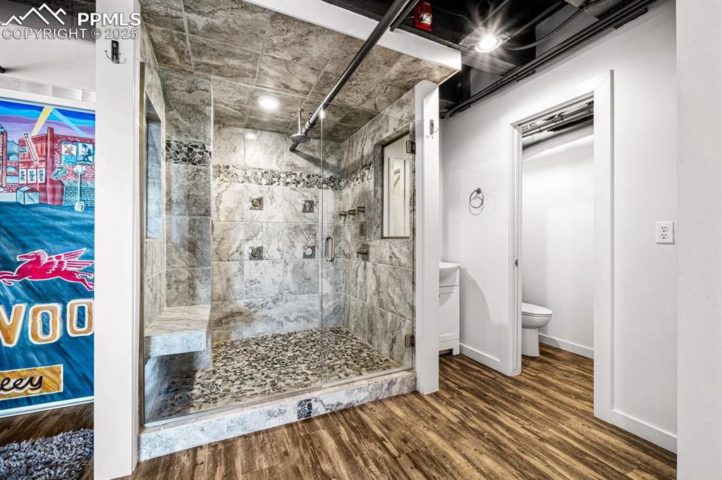 Full bath with a shower stall and wood finished floors