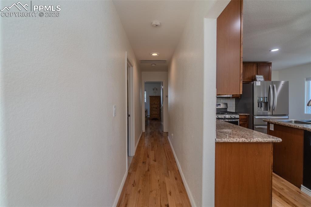 Corridor with light wood-type flooring and recessed lighting