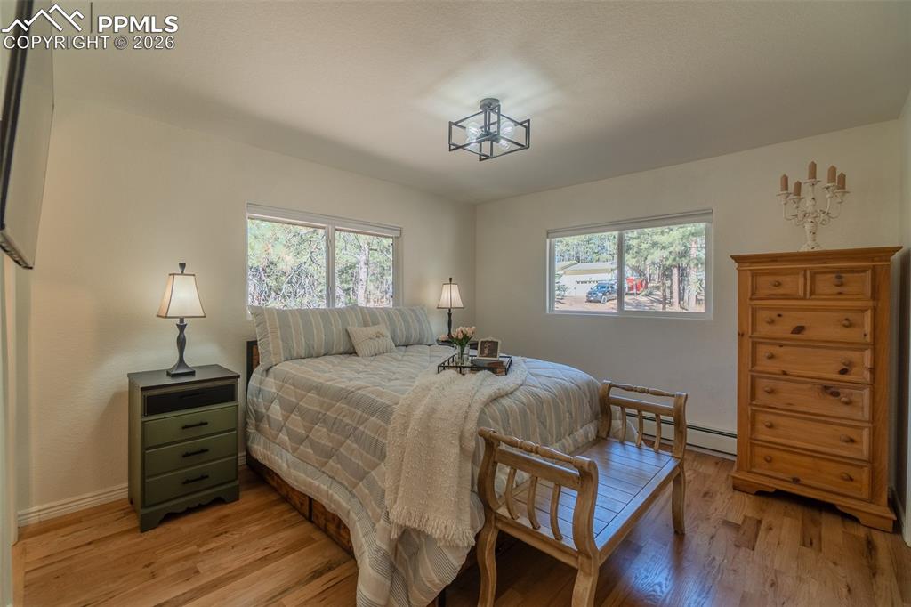 Primary Bedroom on main level featuring light wood-type flooring and a baseboard radiator