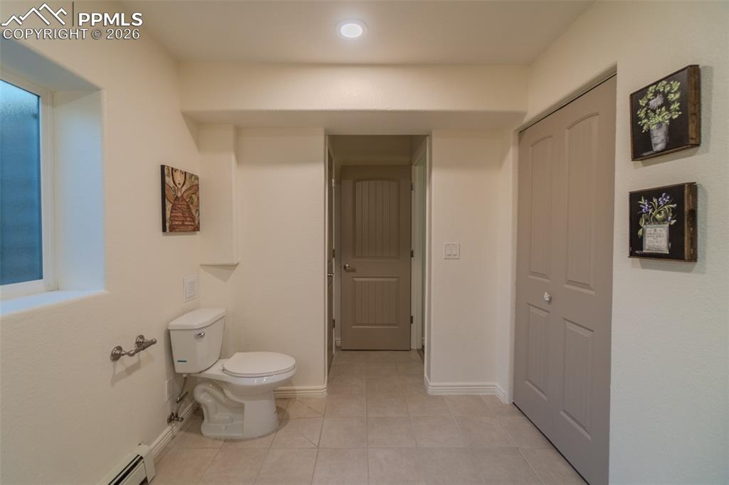 Lower Level Bathroom featuring a baseboard radiator and light tile patterned floors