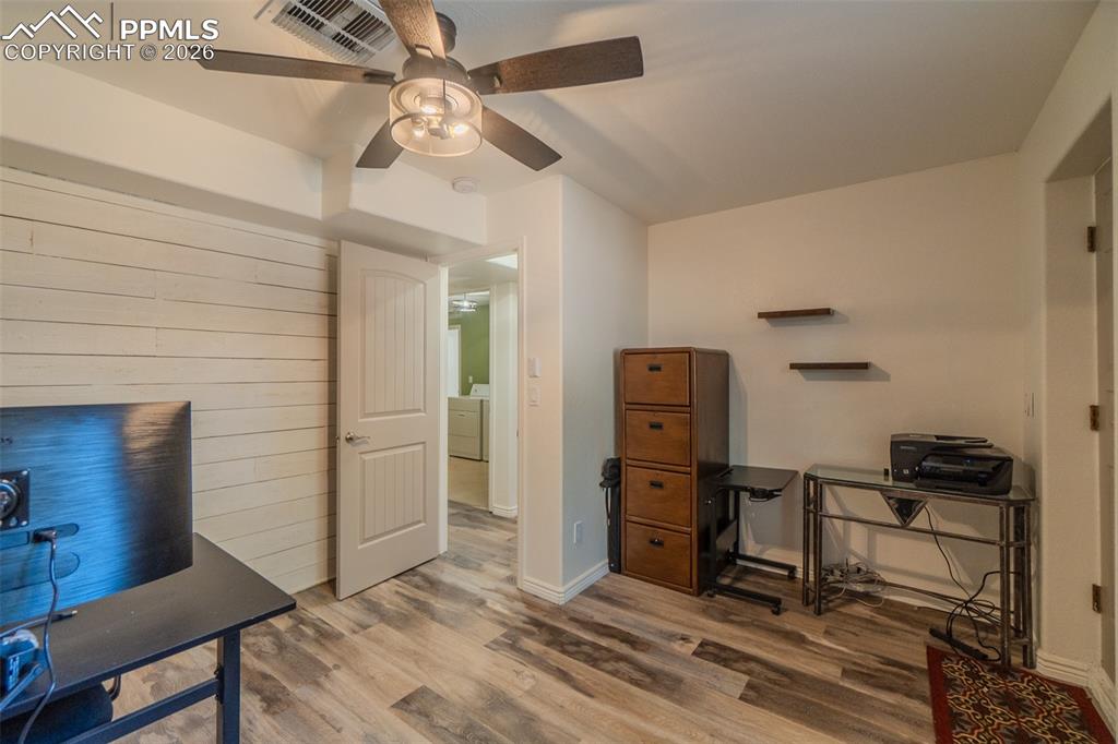 5th lower level bedroom wood finished floors, washer / clothes dryer, and a ceiling fan
