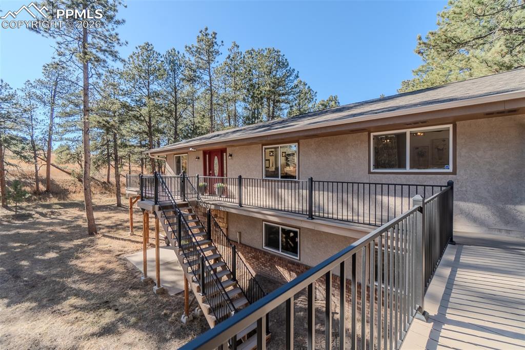 Rear view of property with stairs and stucco siding