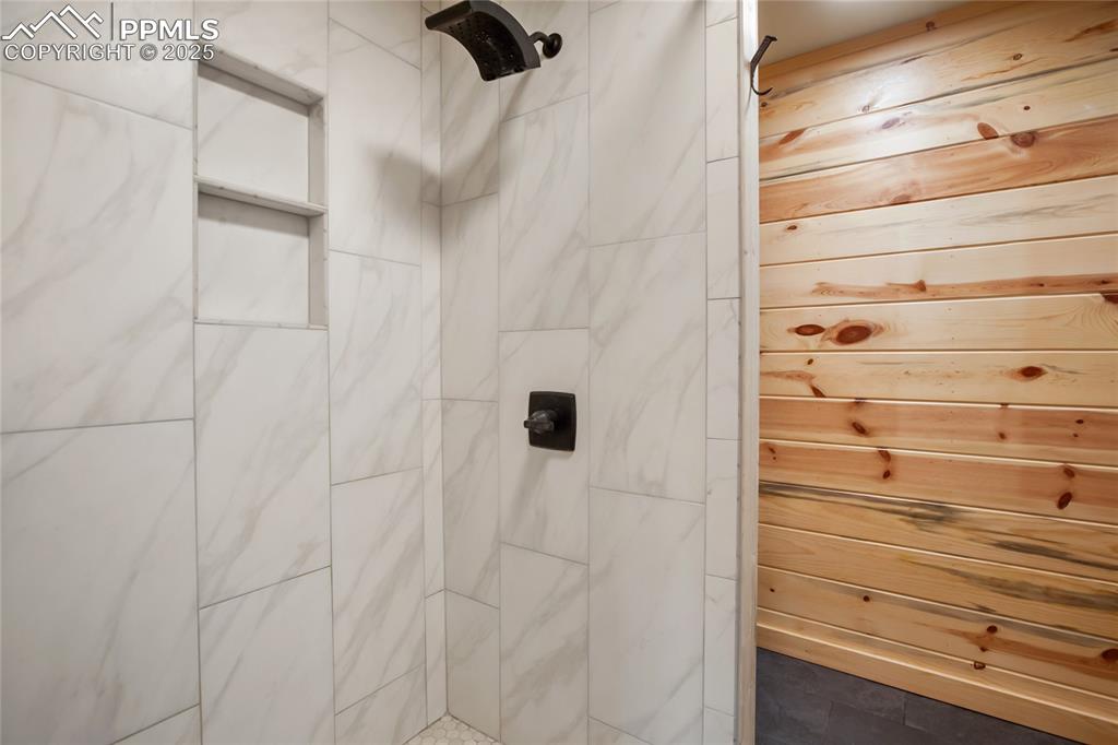 Bathroom featuring a tile shower and wood walls