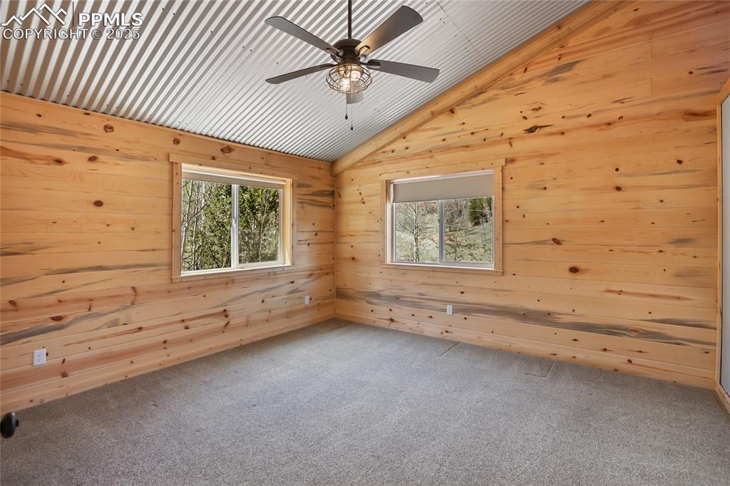 Bedroom #3 with pine paneling, carpet and ceiling fan. Lots of natural light!
