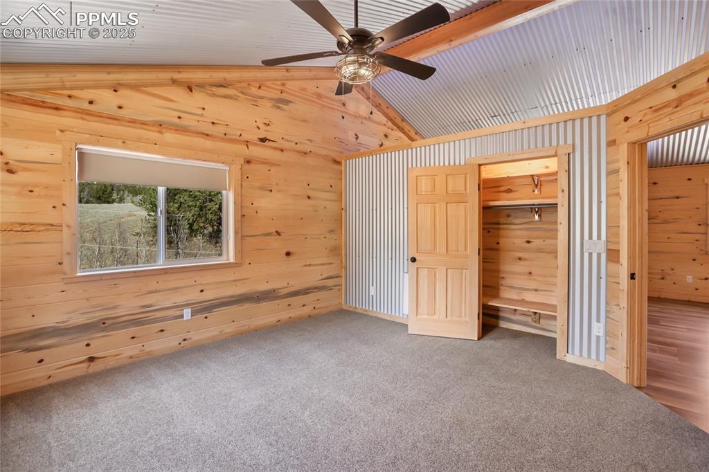 Bedroom #3 with pine paneling, metal accents, carpet floors and ceiling fan